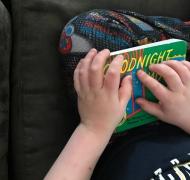 Liam reading the braille tape on the cover of Goodnight Moon