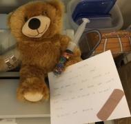 a teddy bear holding a note to nurse in braille