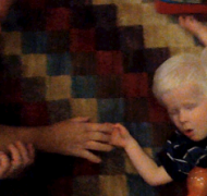 A young boy touches his father's fingers.