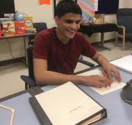A teenage boy reading a page of braille