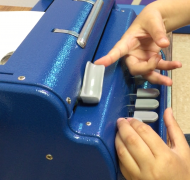 Student returning carriage on braille writer