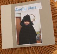 the cover of a tactile book showing a picture of a girl wearing a winter coat and hat and the title Analelia Likes