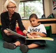 Teacher reading braille book with young boy