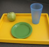 yellow tray with green plate, an apple and a blue cup