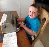 A boy writes a letter on a braillewriter.