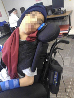 A boy in a wheelchair activates a switch using his head