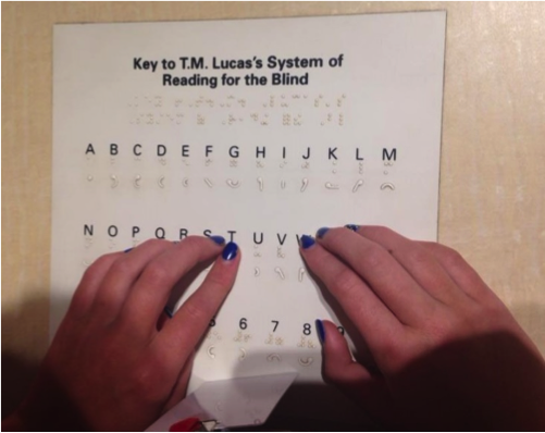Hands on braille document "Key to T. M. Lucas's System of Reading for the Blind"