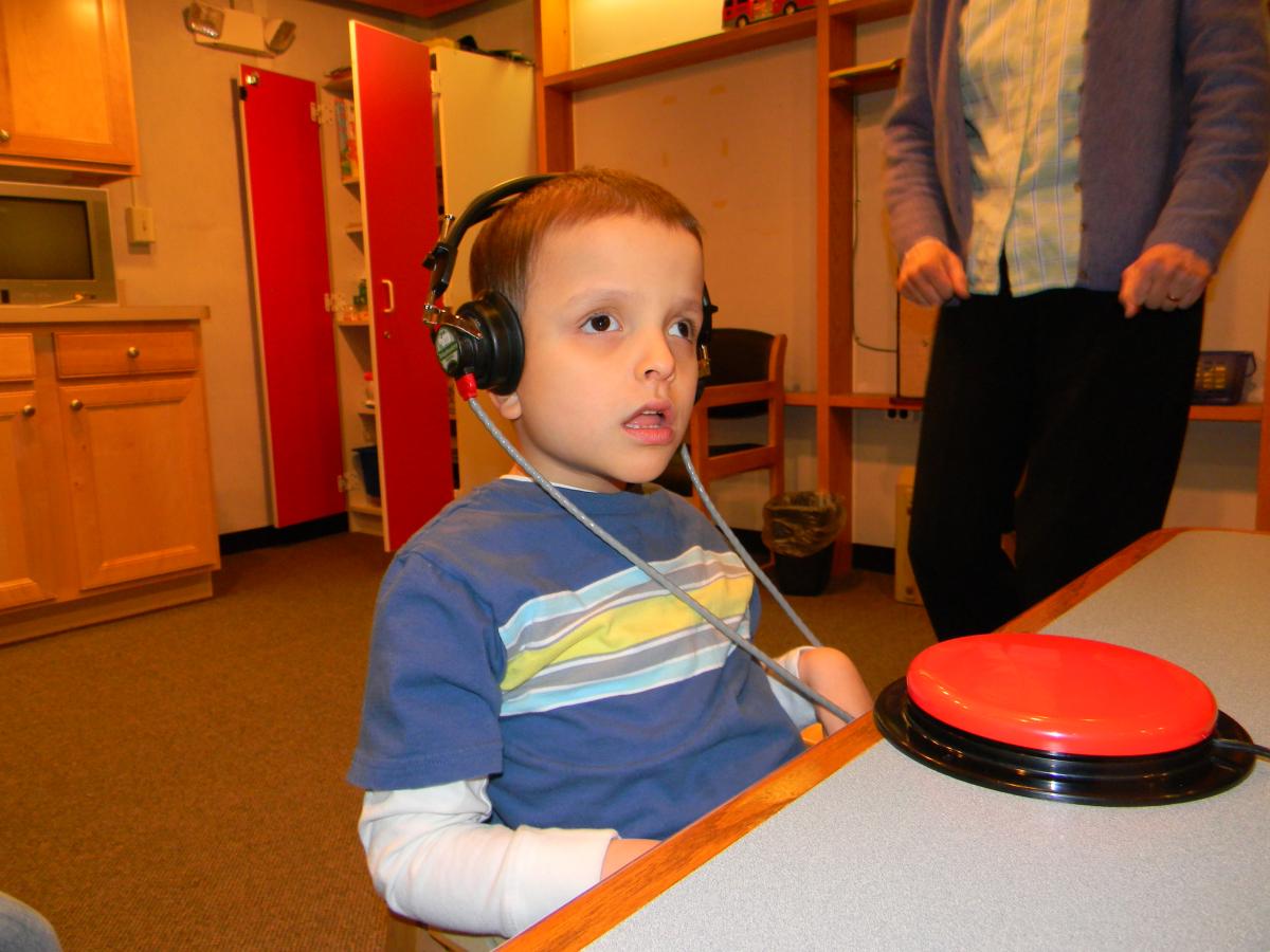 Young boy with headphones and red Big Mac switch on table in front of him.