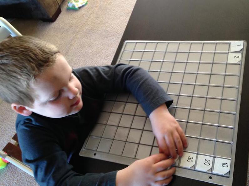 Boy using hundreds chart to count by tens