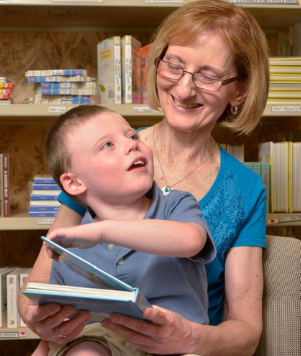 Debra reading a book with a boy sitting on her lap.