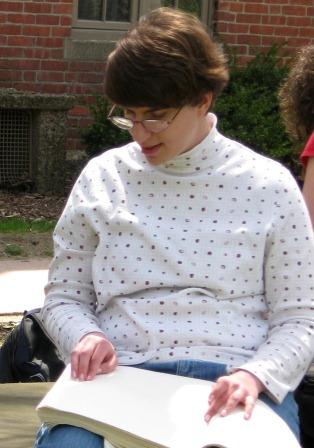 Girl with glasses reads a braille book.