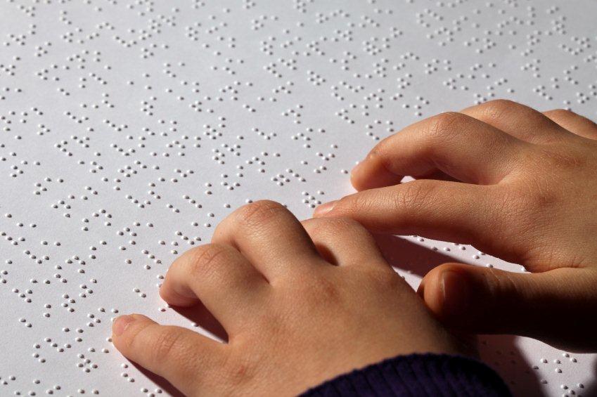 image of girl's hands reading a braille page