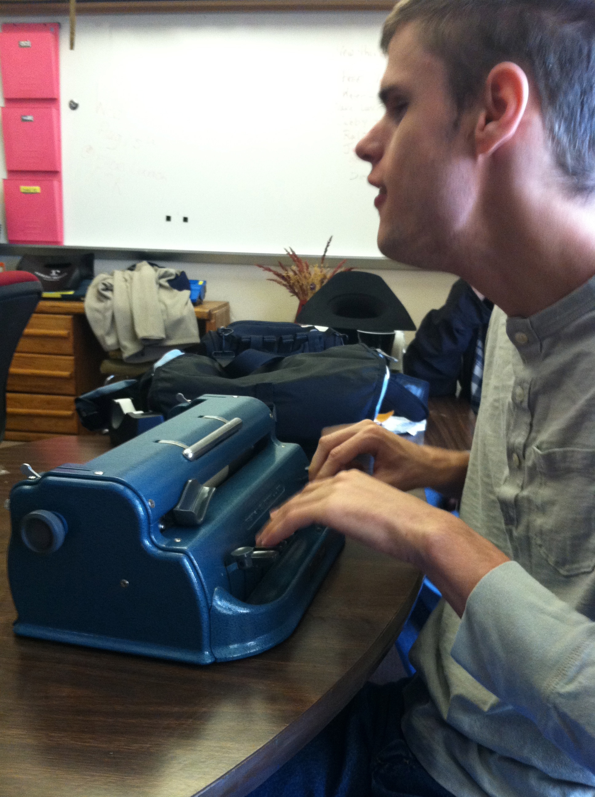 Photo: Student at table working on his braillewriter