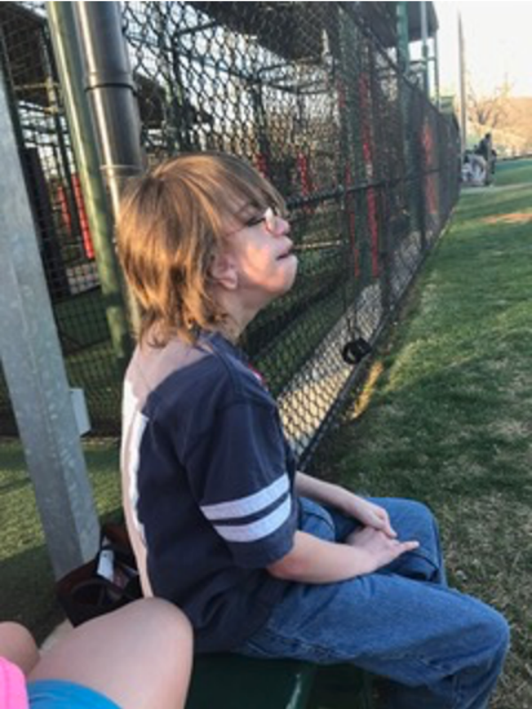 Boy sitting on bench at athletic field