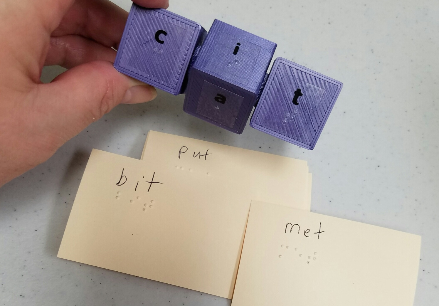 Picture of word cube with braille labels and braille word cards