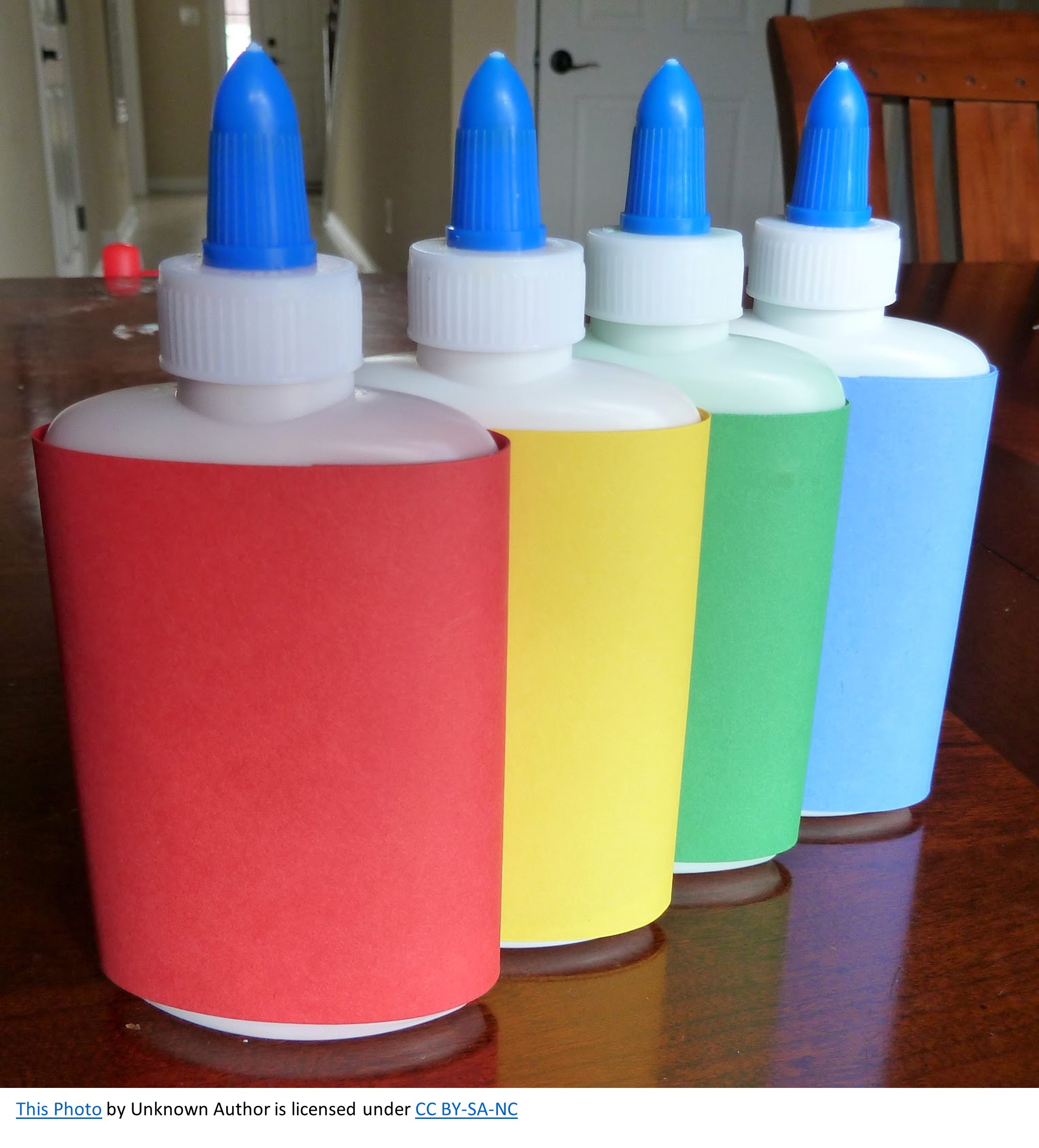 Four squeeze bottles of puff paint colored red, yellow, green, and blue.