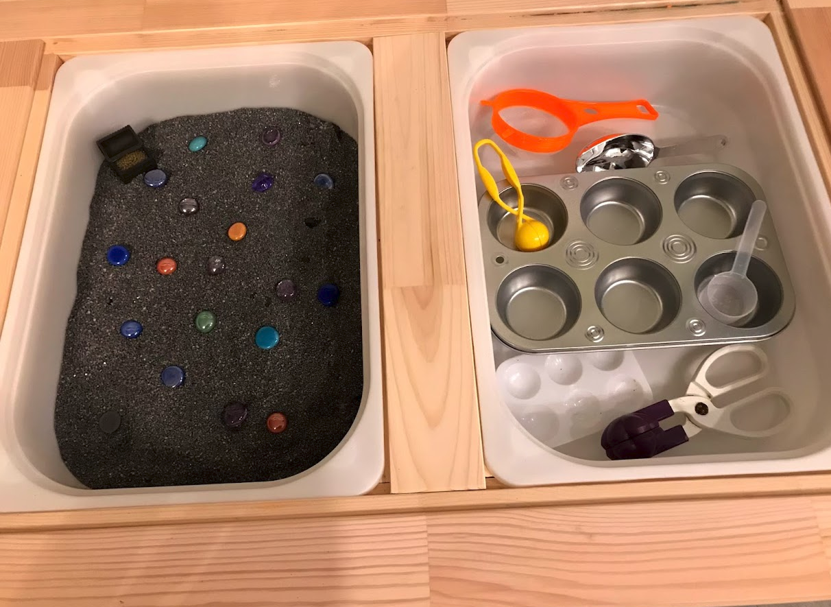Treasure chest sensory bin with fake jewels in sand with scoopers