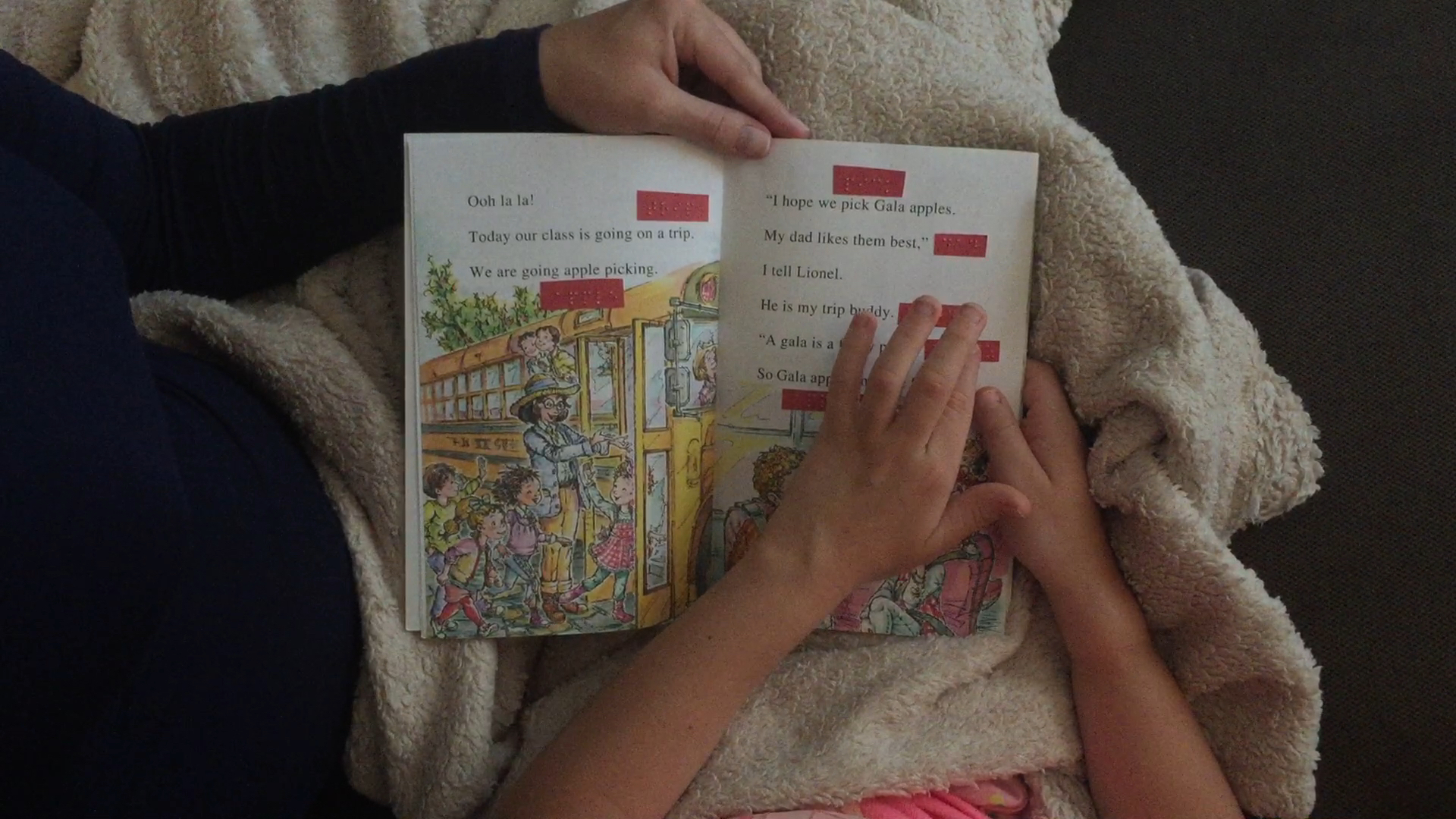 Mom and little girl share a book with print and braille