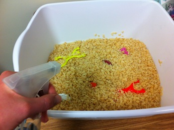 student spraying into a bowl full of rice crispies and toys