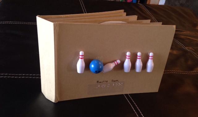 a cardboard book with toy bowling pins and a bowling ball on the cover