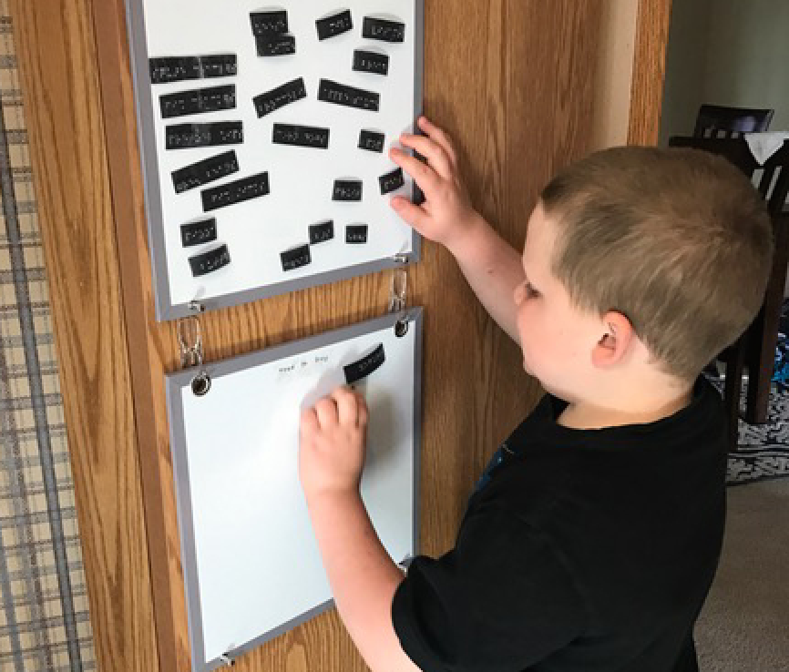 A boy reads a braille grocery list on magnetic strips