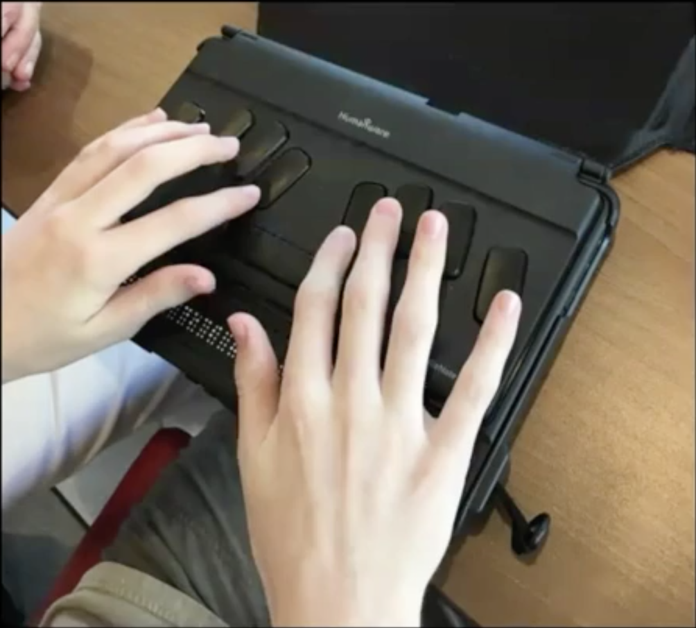 Student writing with a braille notetaker
