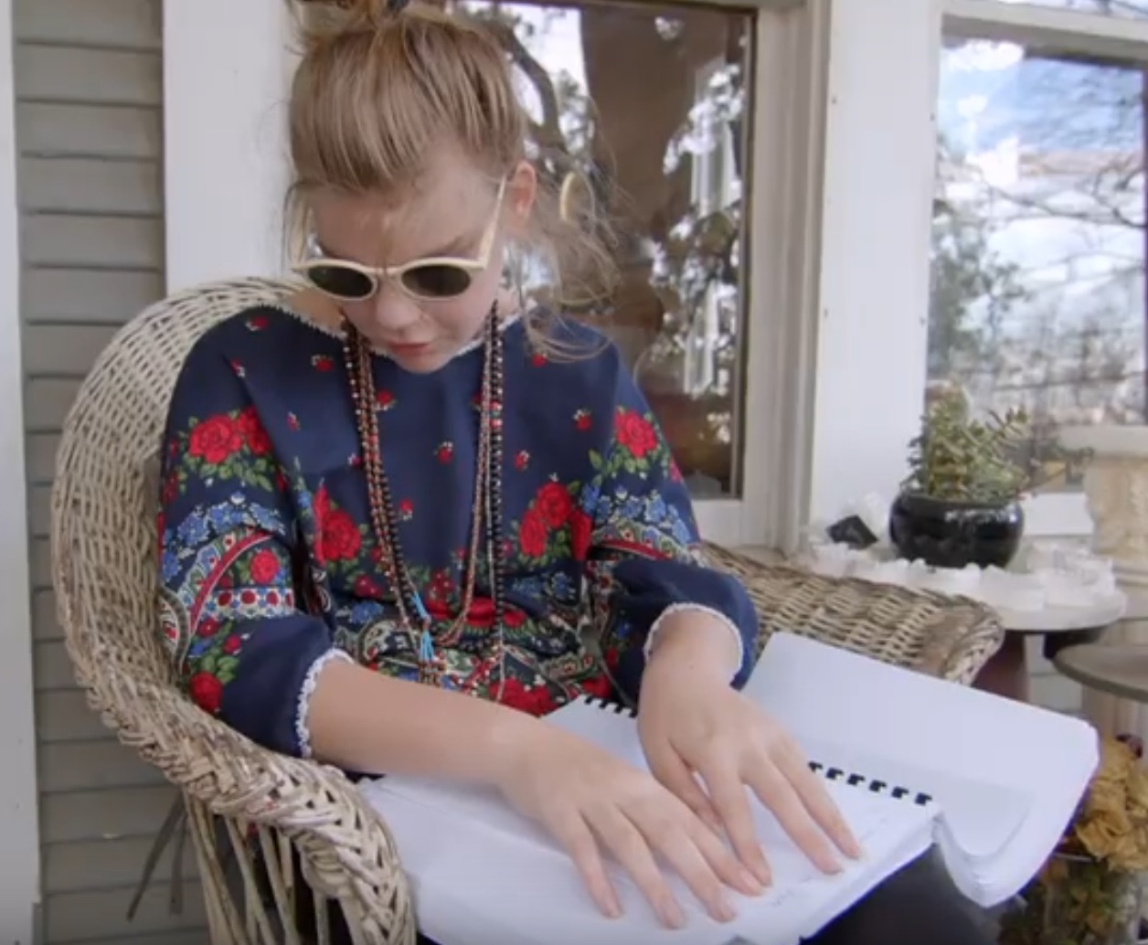 Reading braille book on porch