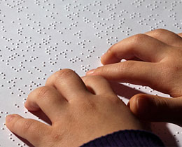 child's hands reading braille