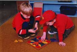 Young children place with math manipulatives on the floor.