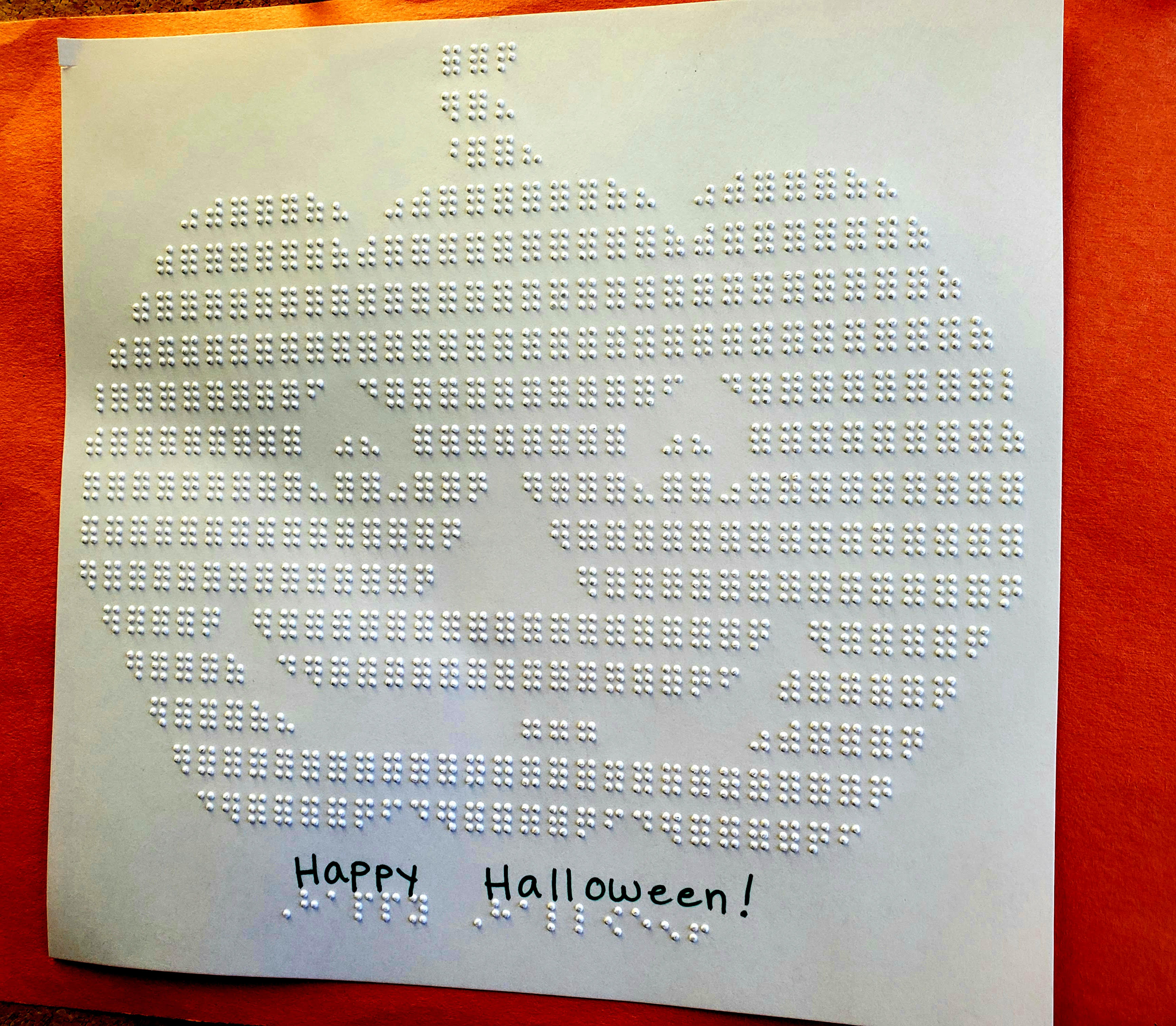 Embossed Jack-o-Lantern with "Happy Halloween" in braille.