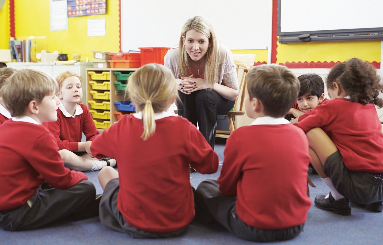 teacher with several students in circle sitting on the floor