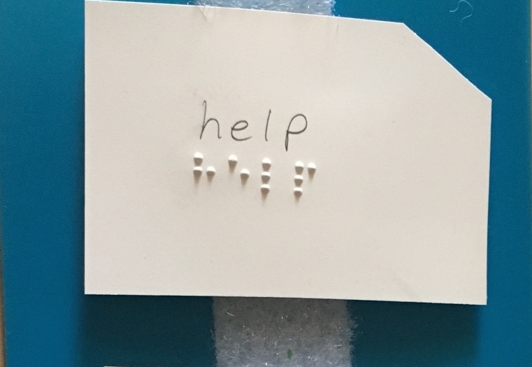 Index card with "help" in print and braille