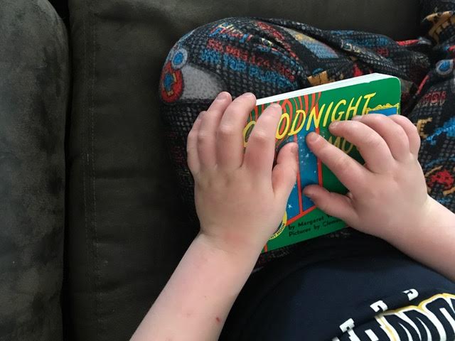 Liam reading the braille tape on the cover of Goodnight Moon