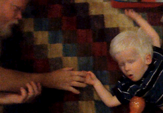 A young boy touches his father's fingers.