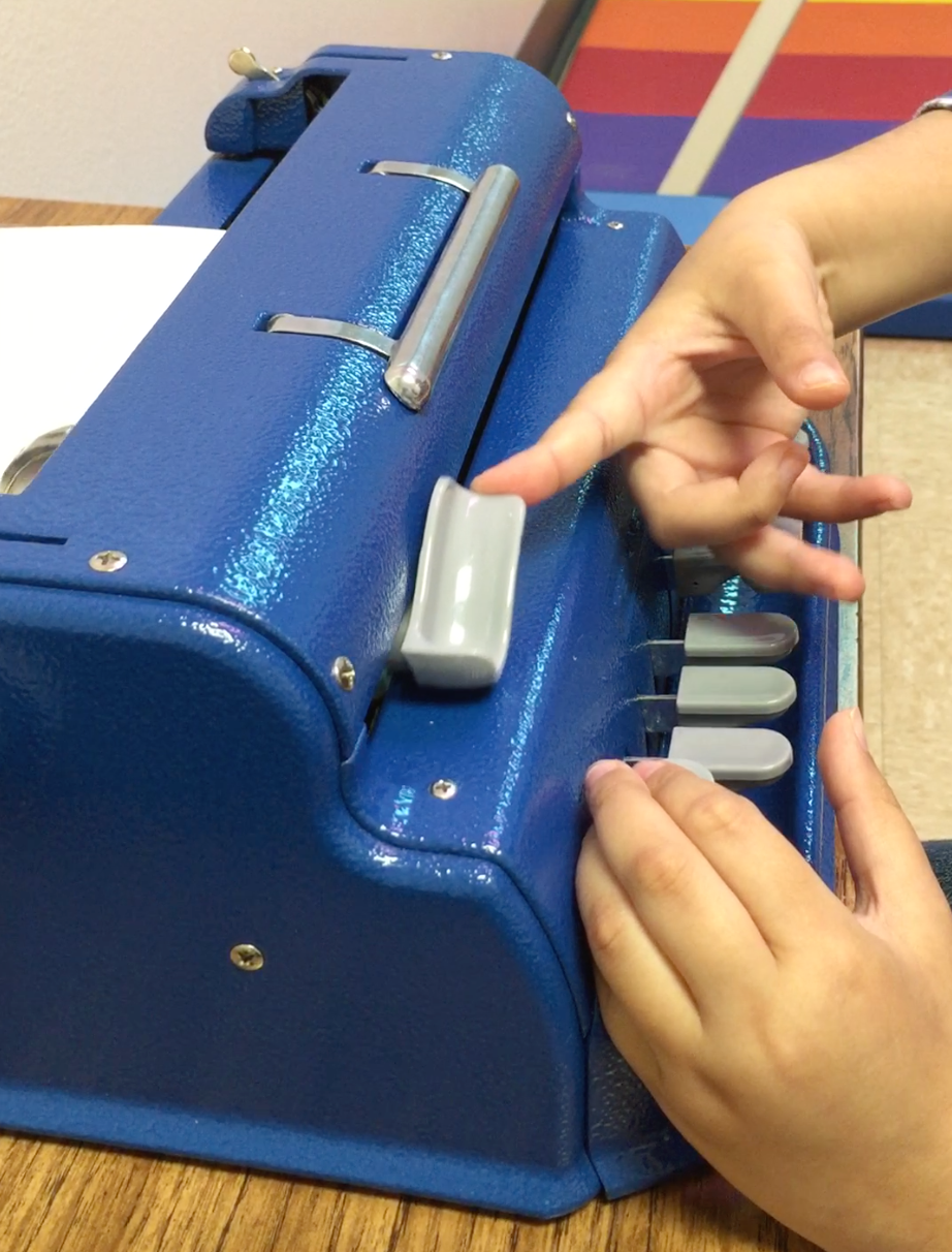 Student returning carriage on braille writer