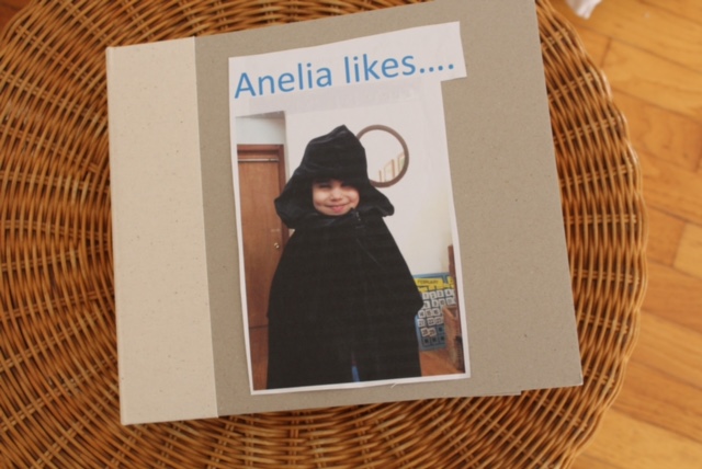 the cover of a tactile book showing a picture of a girl wearing a winter coat and hat and the title Analelia Likes