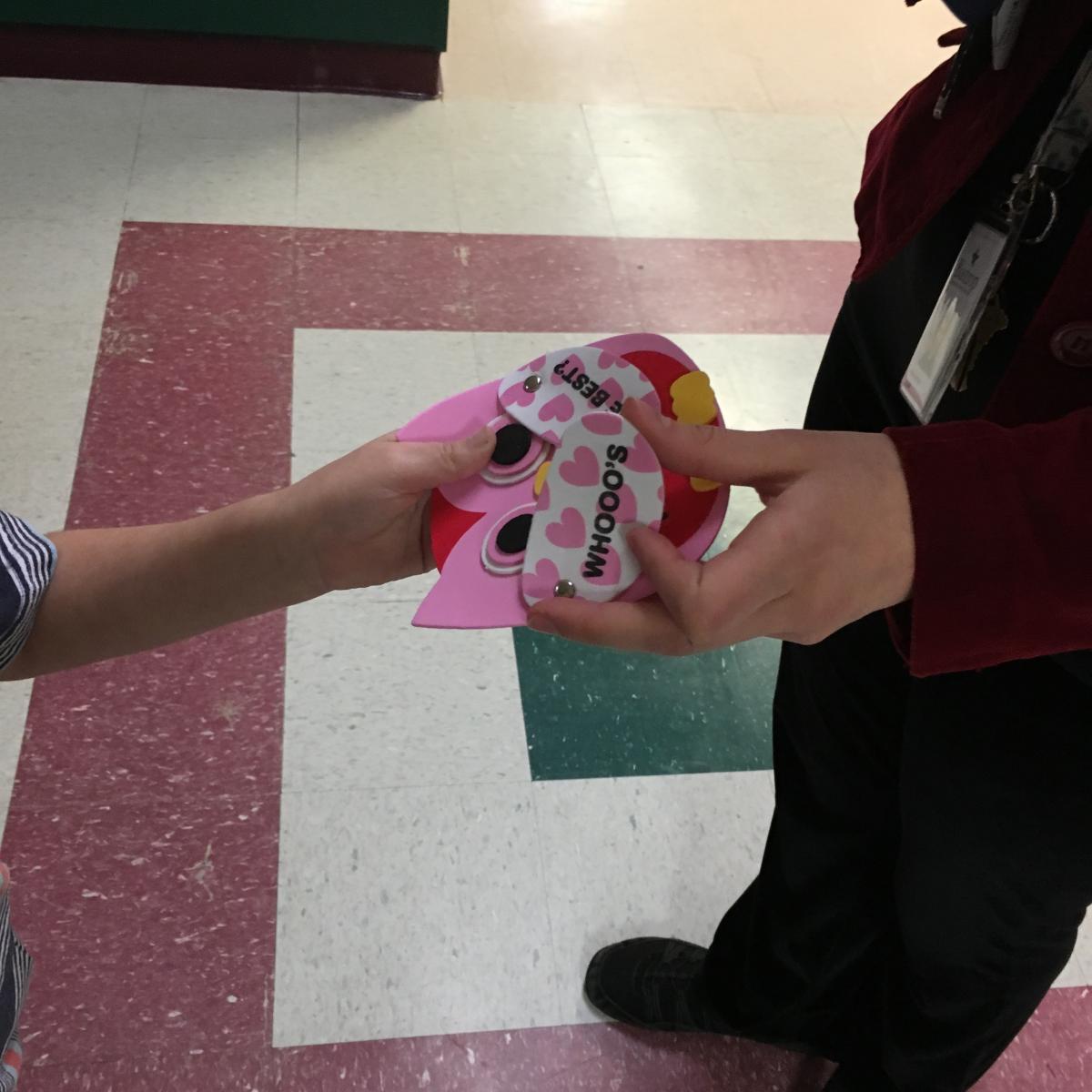 A student hands a valentine to an adult.