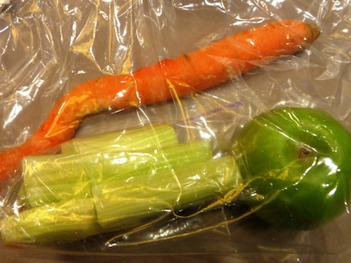 bag with sticks of celery, a carrot, and an apple